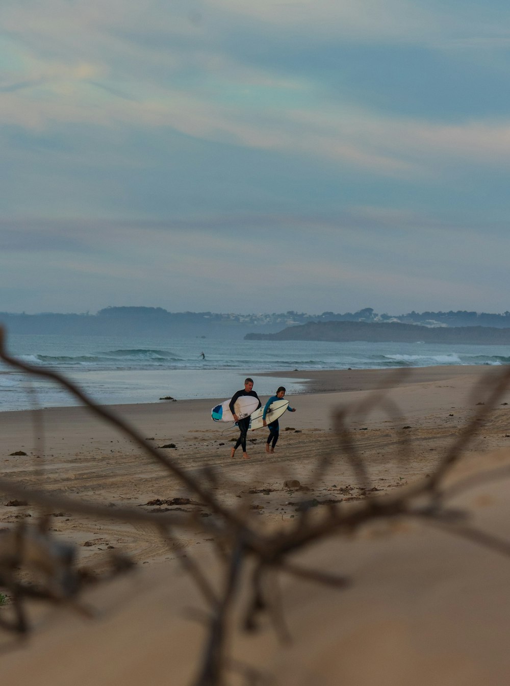 man and woman holding surfboards