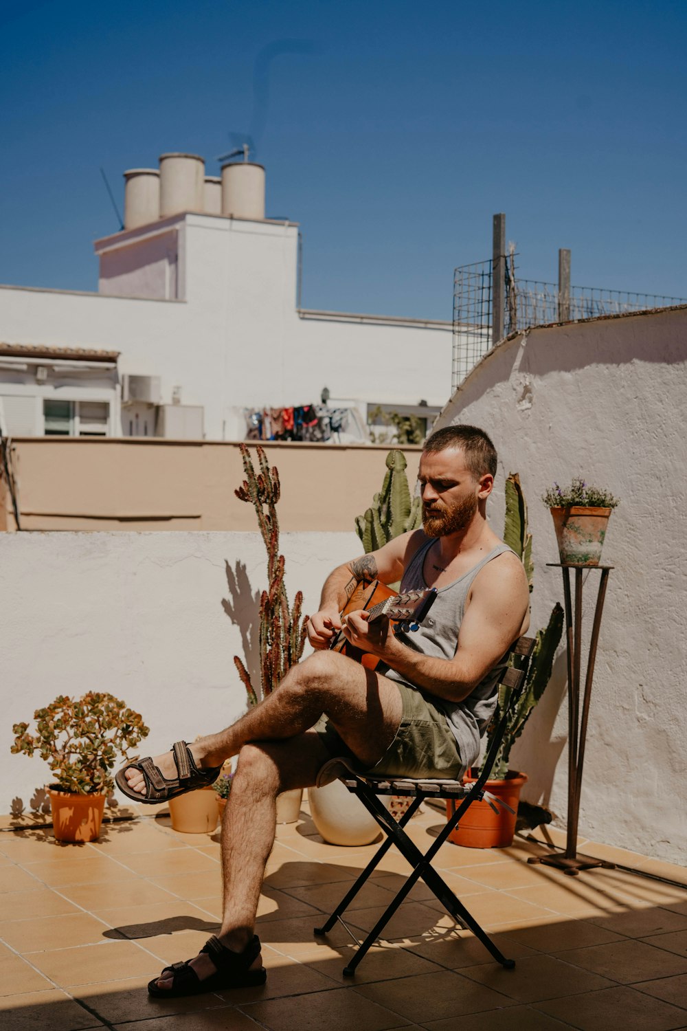 man siting on black chair while playing brown guitar