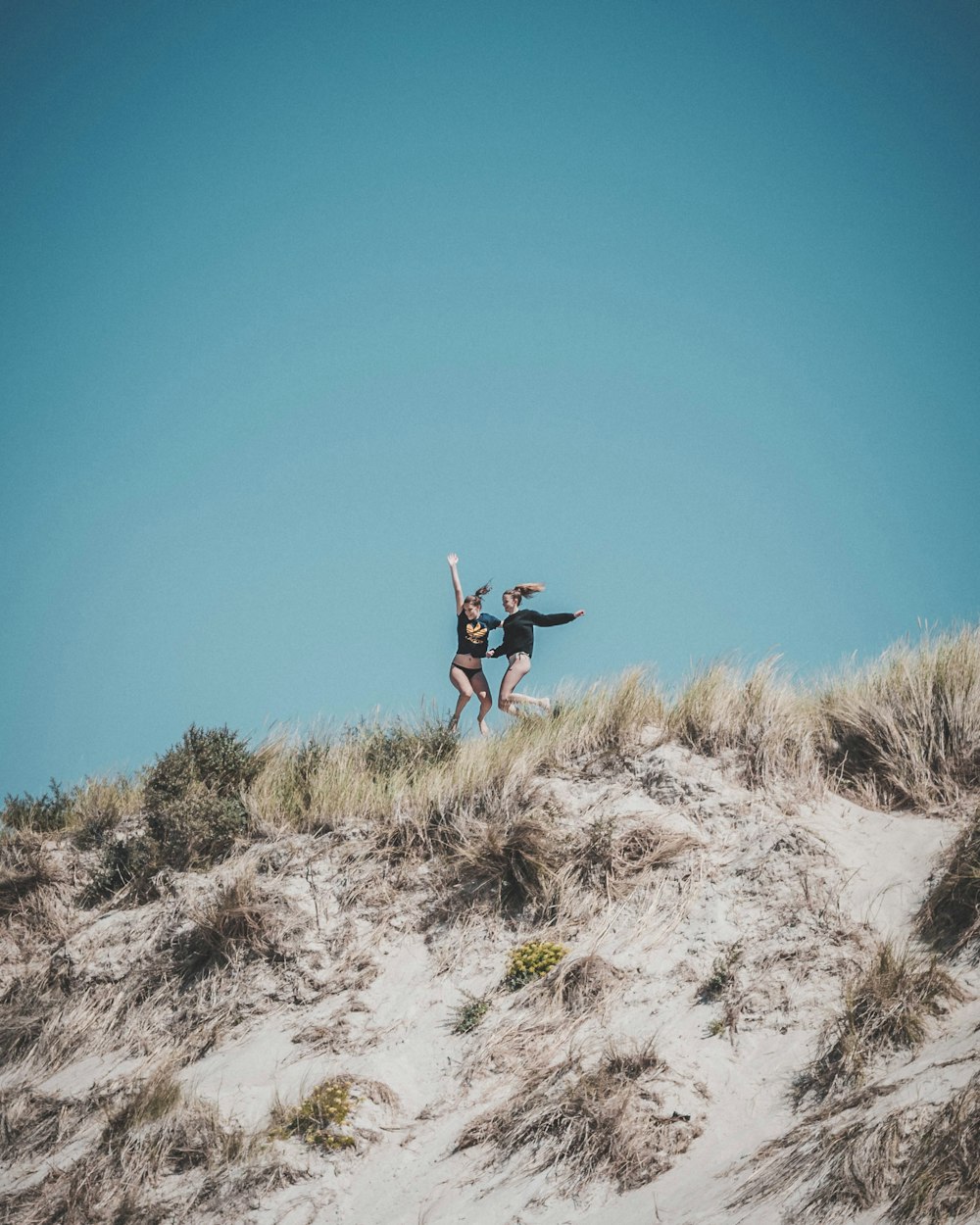 two woman jumping during daytime