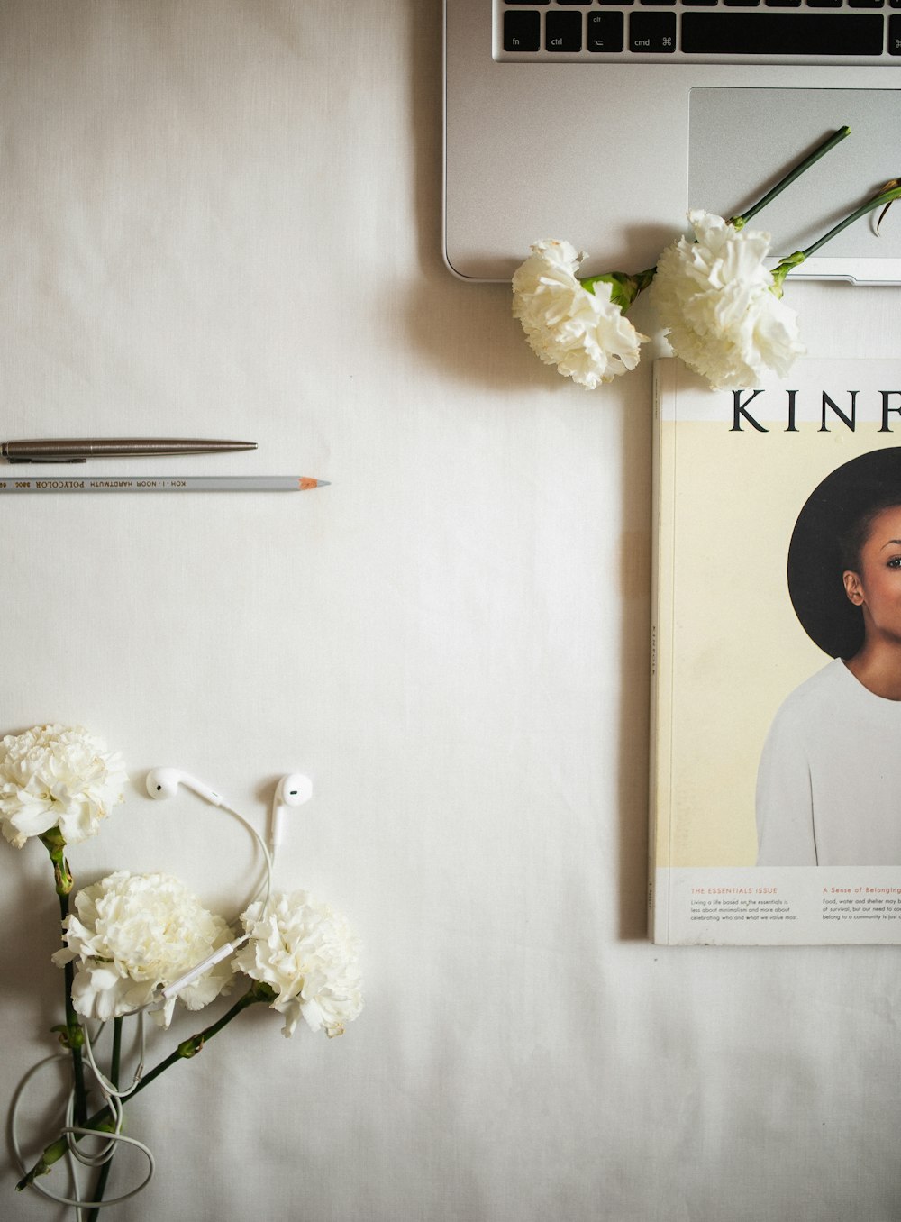 a desk with a magazine and flowers on it