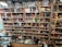A well-organized liquor store shelf stacked with a variety of alcoholic beverages. Numerous bottles of whisky, wine, and spirits are displayed in rows, categorized by type and brand. The shelves are made of wood, providing a warm and inviting ambiance. The checkout counter is visible in the foreground, equipped with cash registers and various promotional materials.
