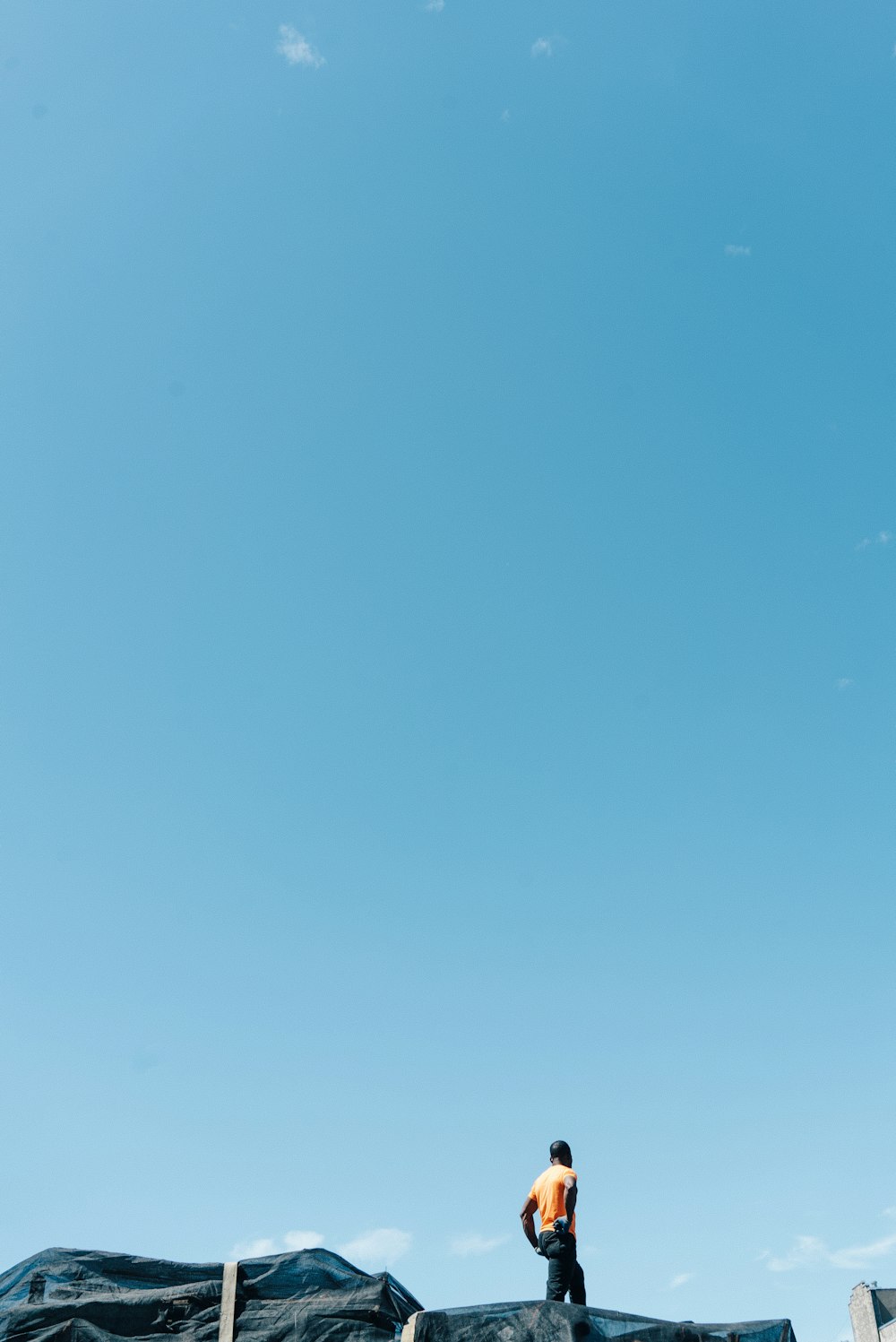 topless man standing on black rock