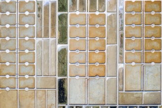 An aerial view of a series of rectangular plots, likely salt flats or evaporation pools, arranged in a grid pattern. Each section varies in color and texture, possibly indicating different stages of evaporation or mineral concentration.
