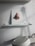 A sculpted nose is mounted on a small white shelf, with a white wall backdrop. Below the shelf is a white machine with a round top and an attached handle.