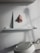 A sculpted nose is mounted on a small white shelf, with a white wall backdrop. Below the shelf is a white machine with a round top and an attached handle.