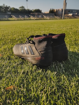 An athlete lacing up Ahmede LLC cleats before a game on hard ground.