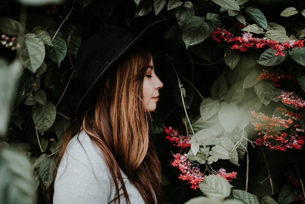 woman sniffing red petaled flower