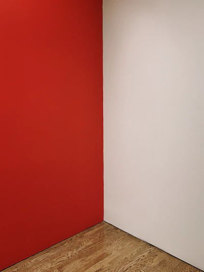 Before and after photo of a freshly painted living room with crisp white walls and bold red accents.