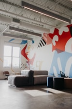 A bright, elegant living room featuring a large, colorful interior mural that sets a sophisticated tone.