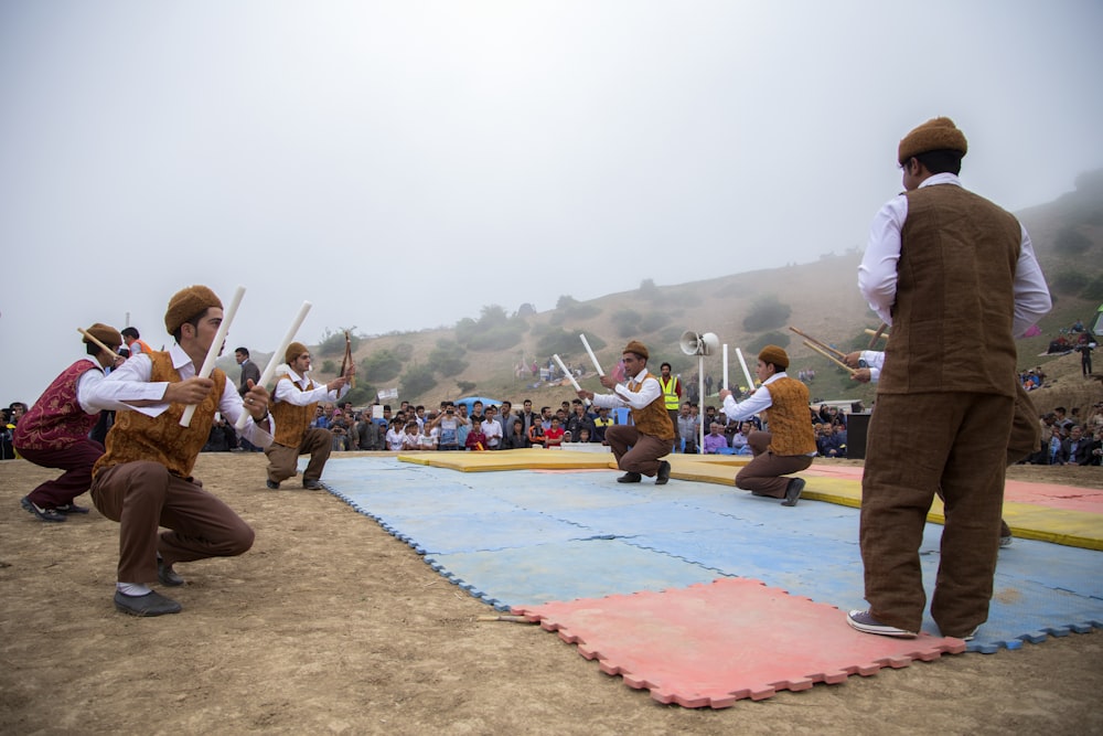 several men holding sticks while squatting in puzzle mat