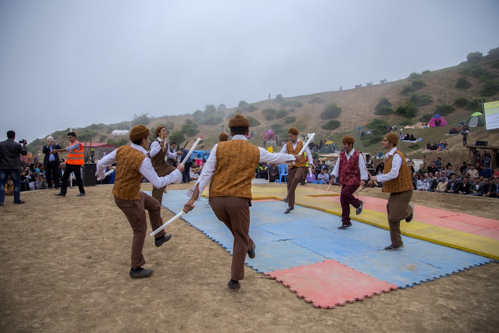 hombres bailando en alfombras de rompecabezas afuera cerca de la gente durante el día