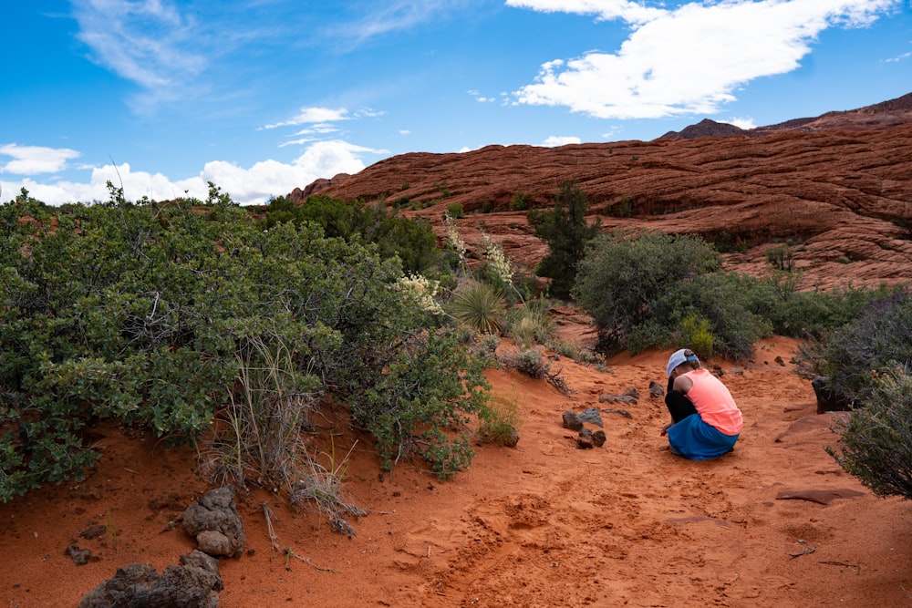 woman taking a knee near hill and shrubs during day