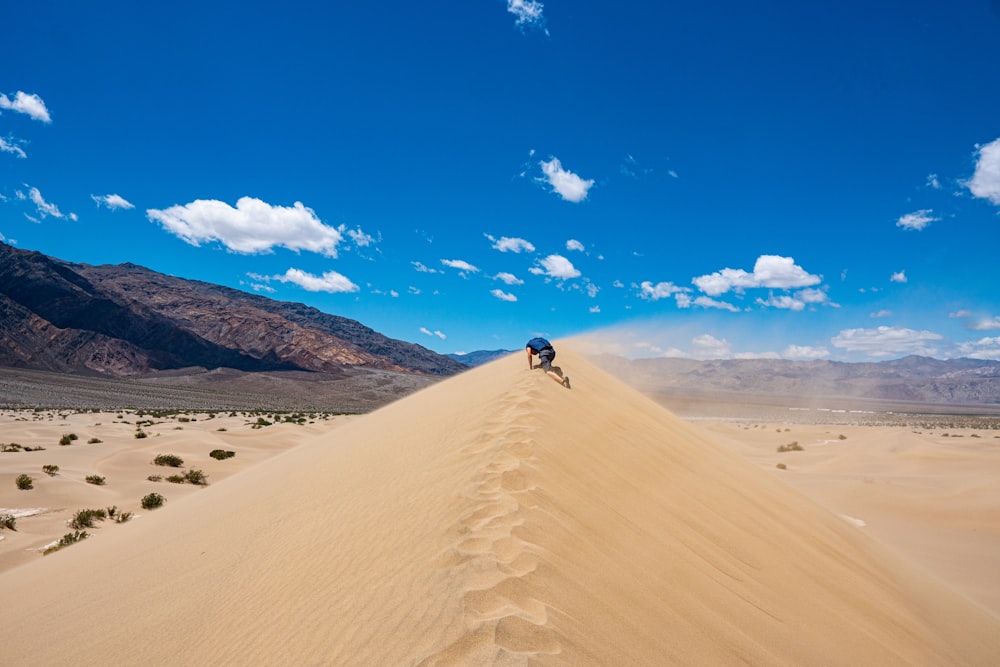 man walking on sand dunes