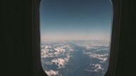 Snow-capped mountains viewed from an airplane window on a clear day.
