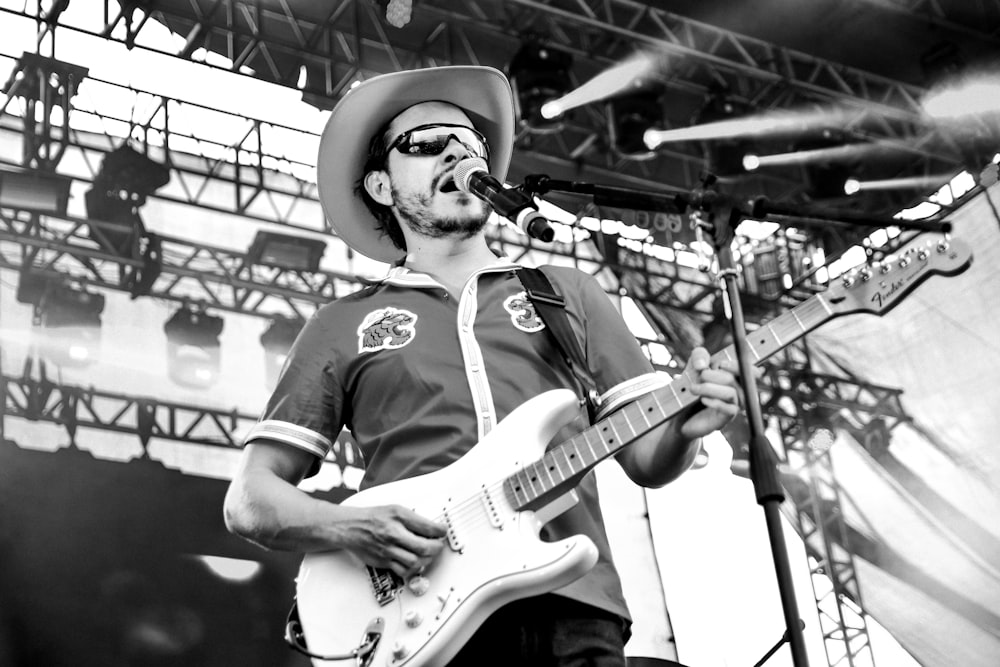 grayscale photo of man playing electric guitar