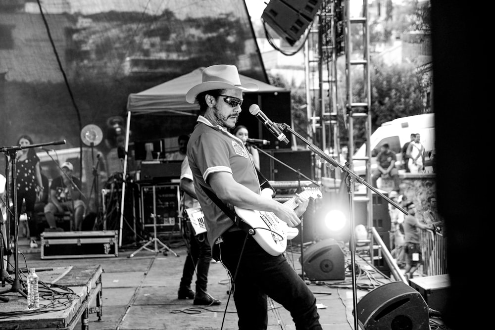 grayscale photograhy of man holding guitar