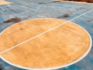 A pair of sturdy knee pads lying on a basketball court floor, showing signs of use.