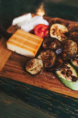 A rustic wooden board featuring an assortment of roasted seasonal vegetables with a sprinkle of fresh rosemary.