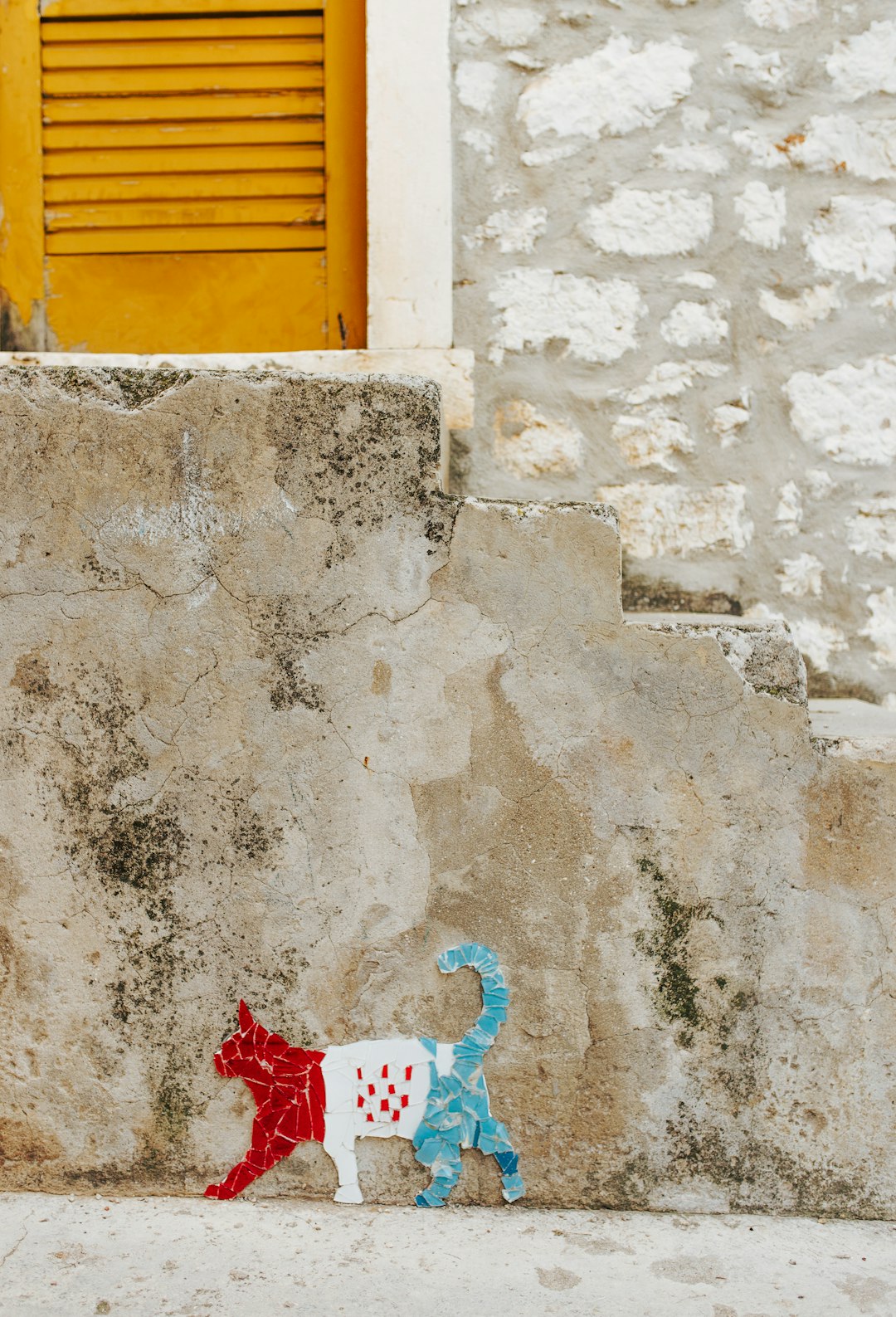 red, white, and green cat paper cut-out near beige concrete wall