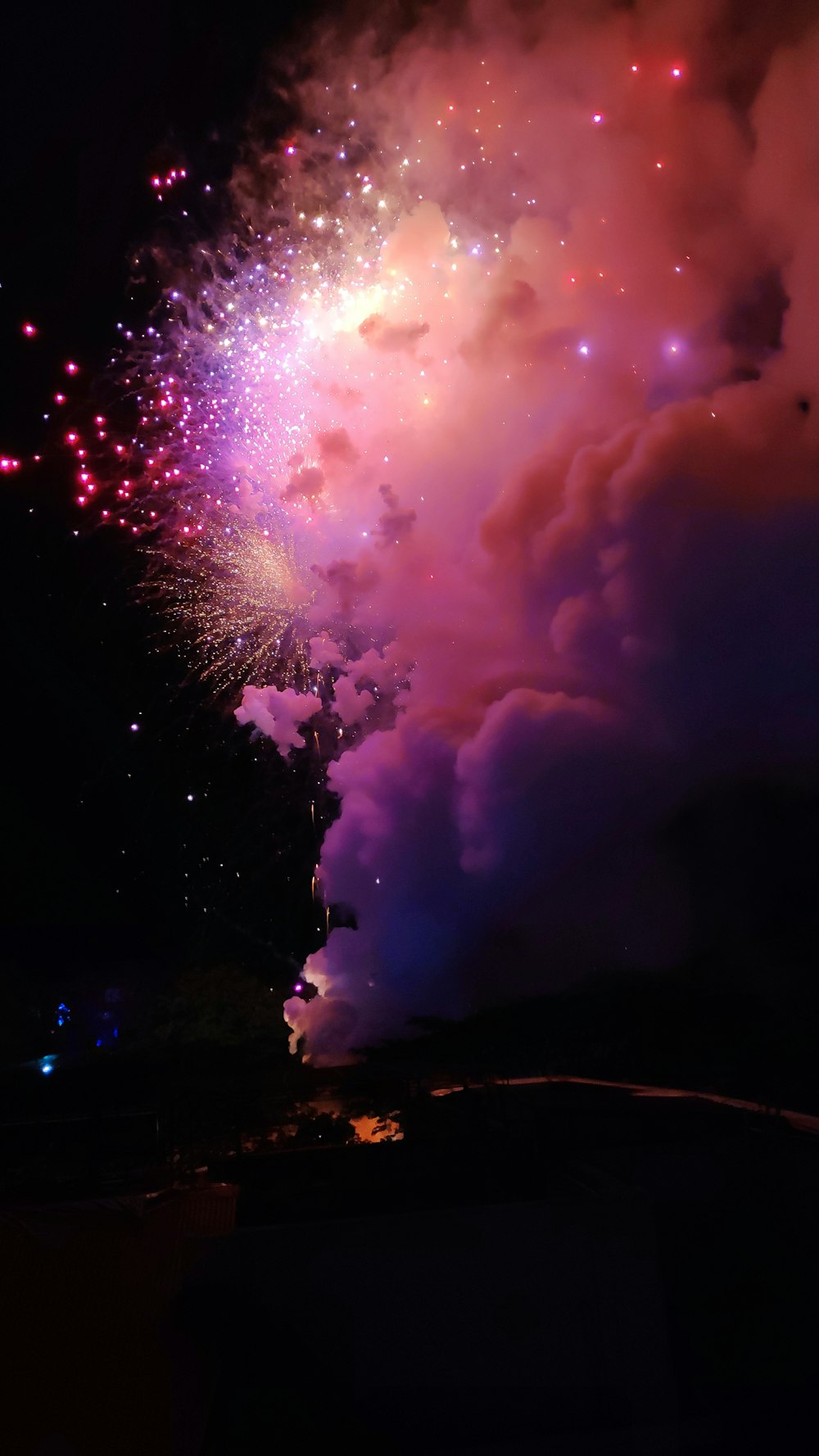 Um fogo-de-artifício colorido é iluminado no céu noturno