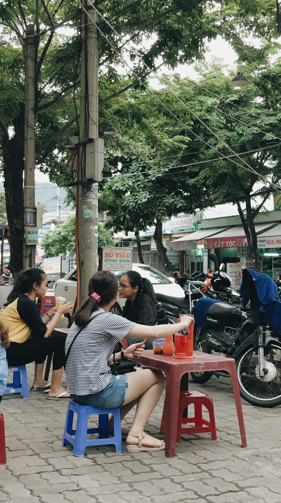 three women sitting near parked black motorcycle