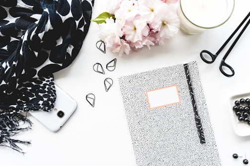 A flat lay of the Olá Mulher notebook surrounded by pens, flowers, and a cup of tea.