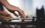 Close-up of a DJ spinning vinyl records, fingers deftly adjusting the turntable’s pitch.
