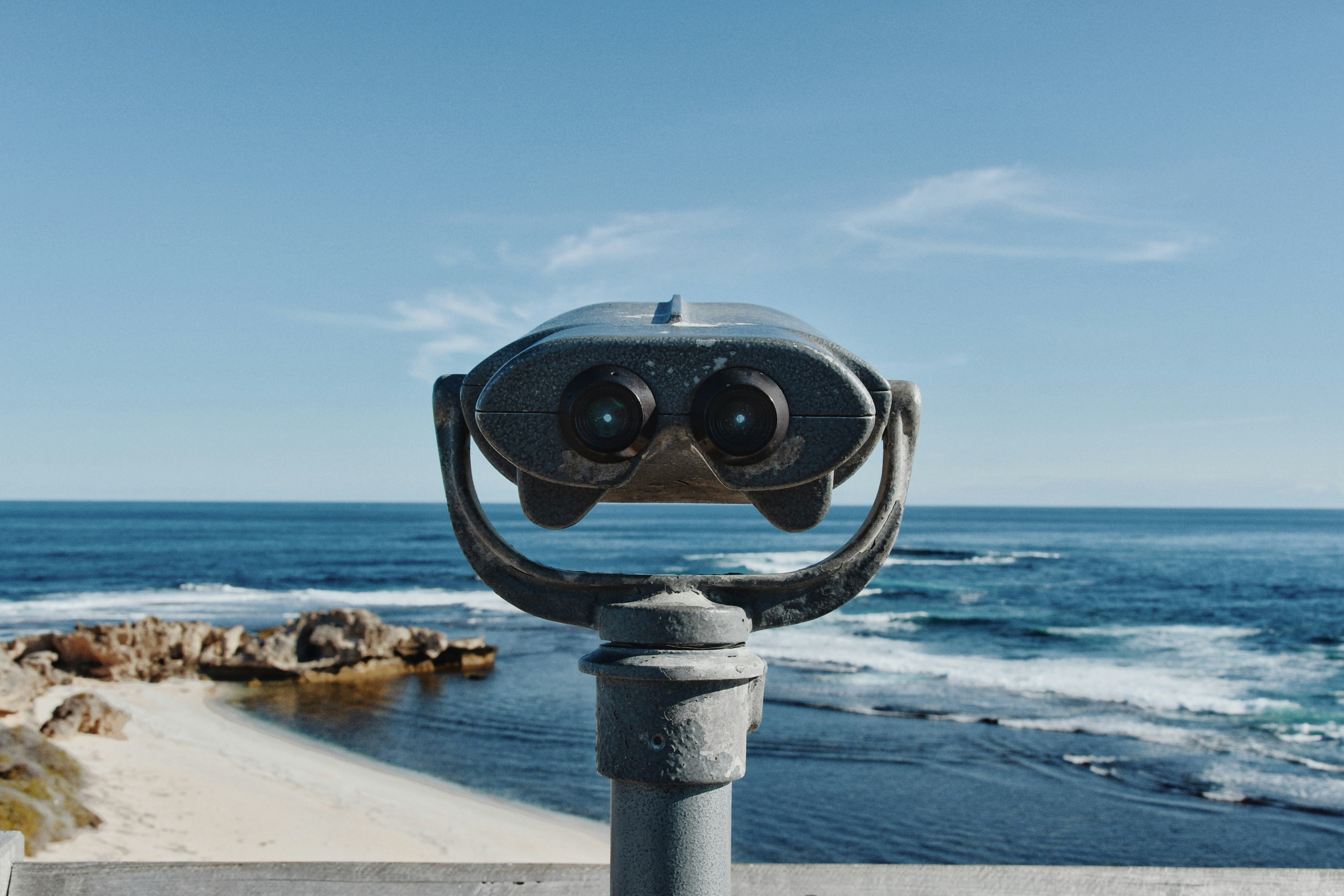 gray binocular with stand facing seashore
