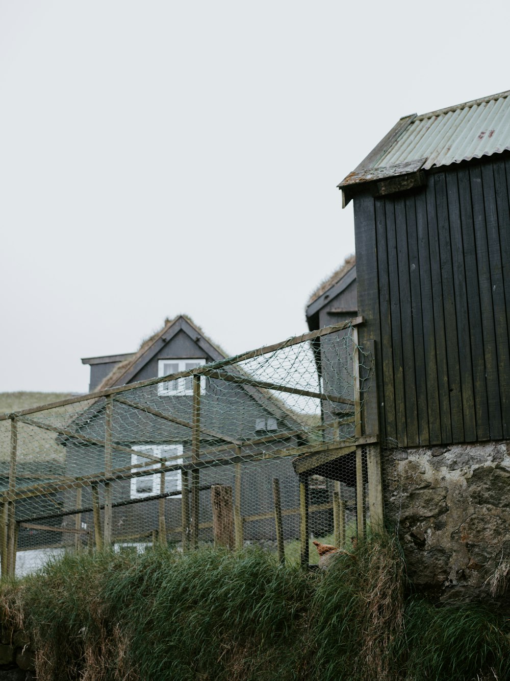 a black building with a metal roof next to a fence