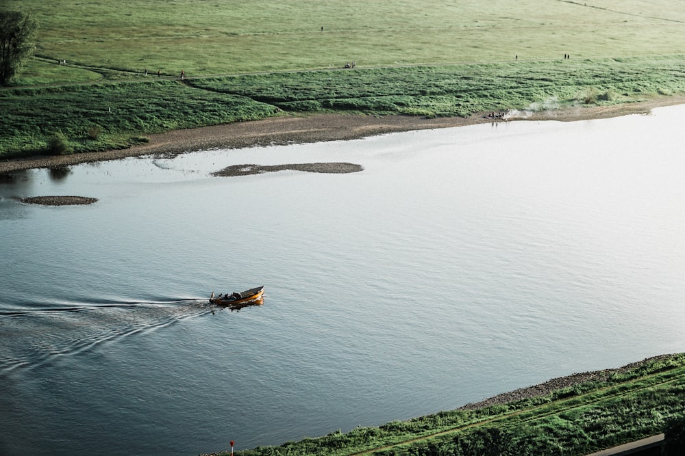 brown boat on river surrounded by green grass