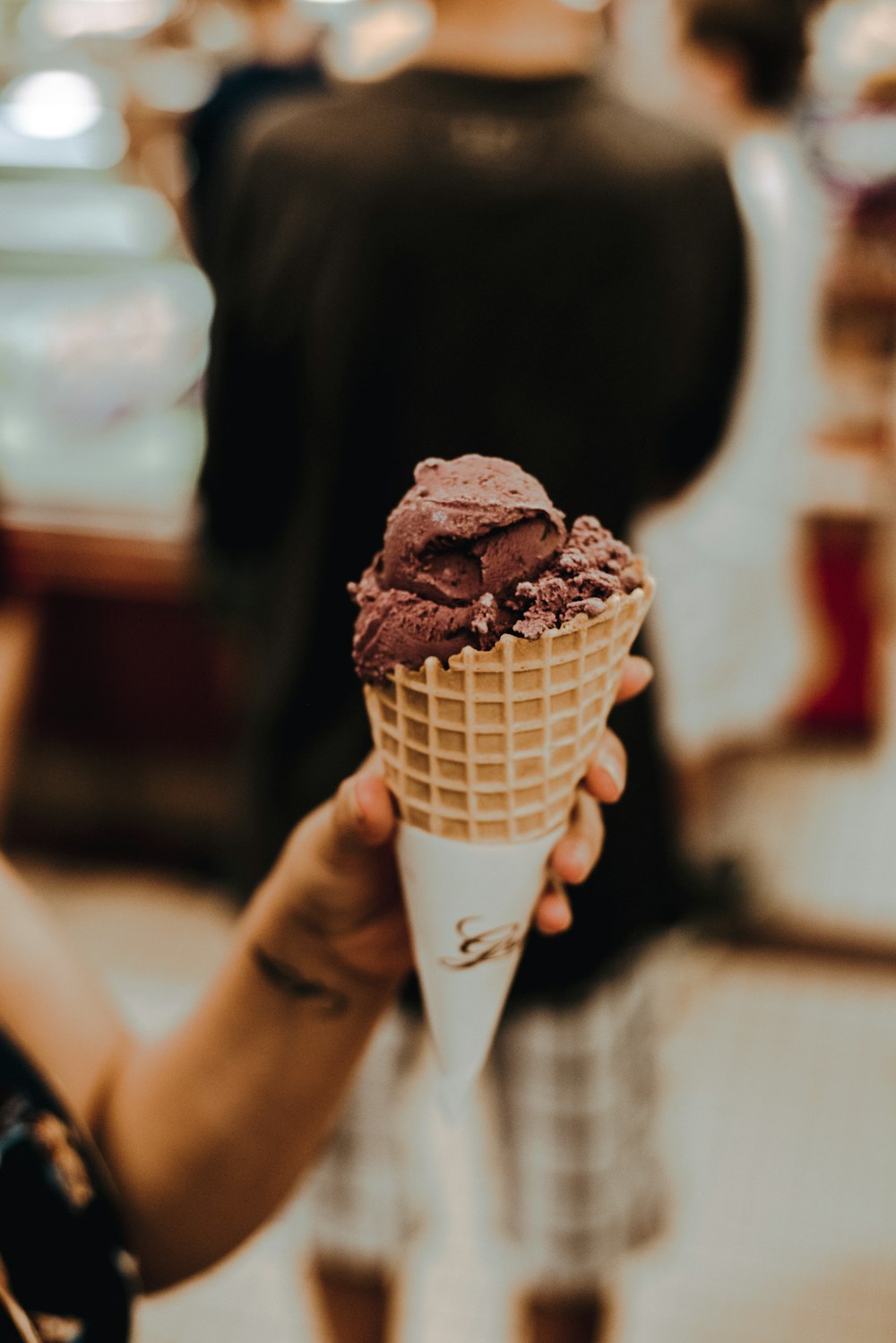 shallow focus photo of person holding ice cream on sugar cone
