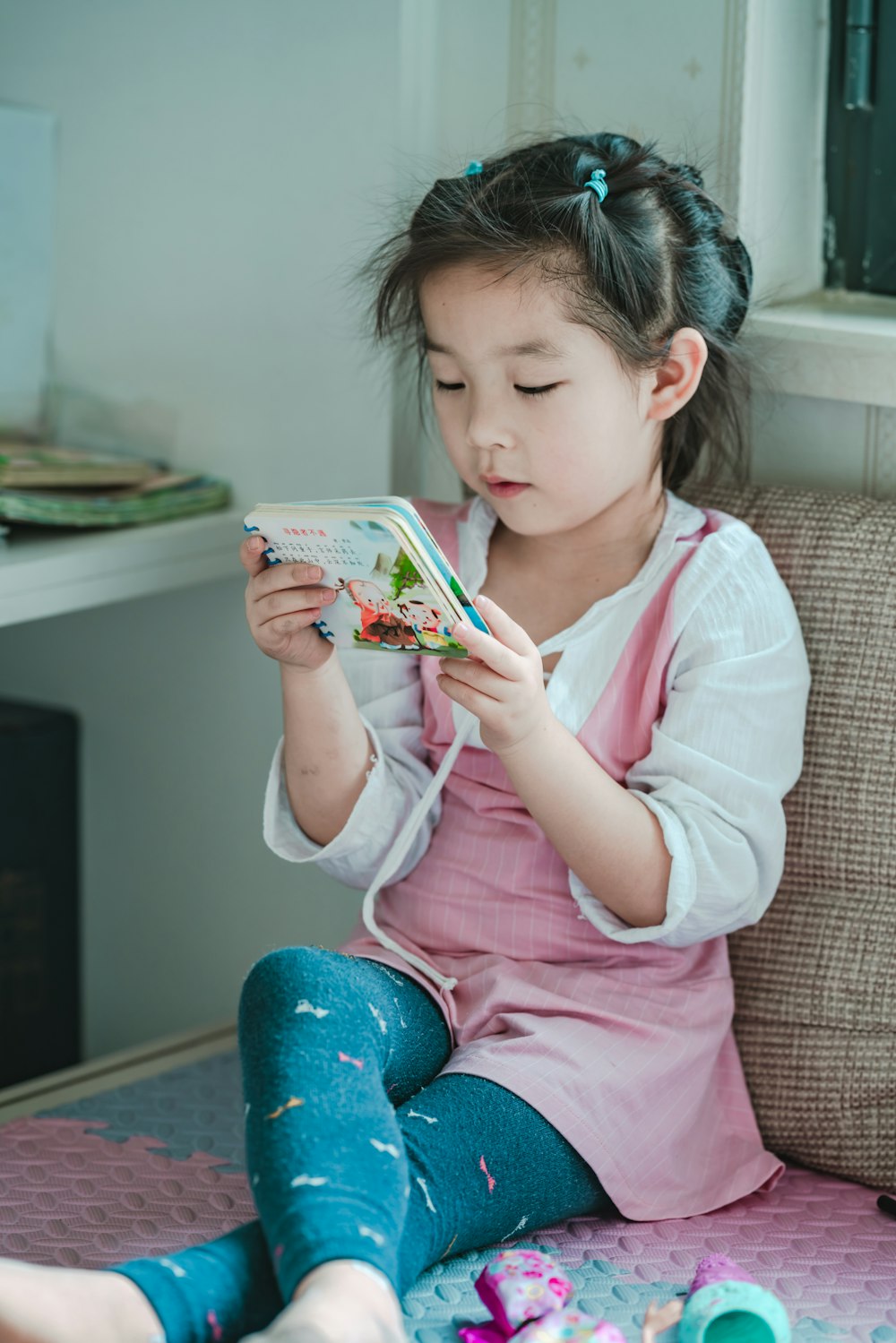 girl reading book while sitting chair