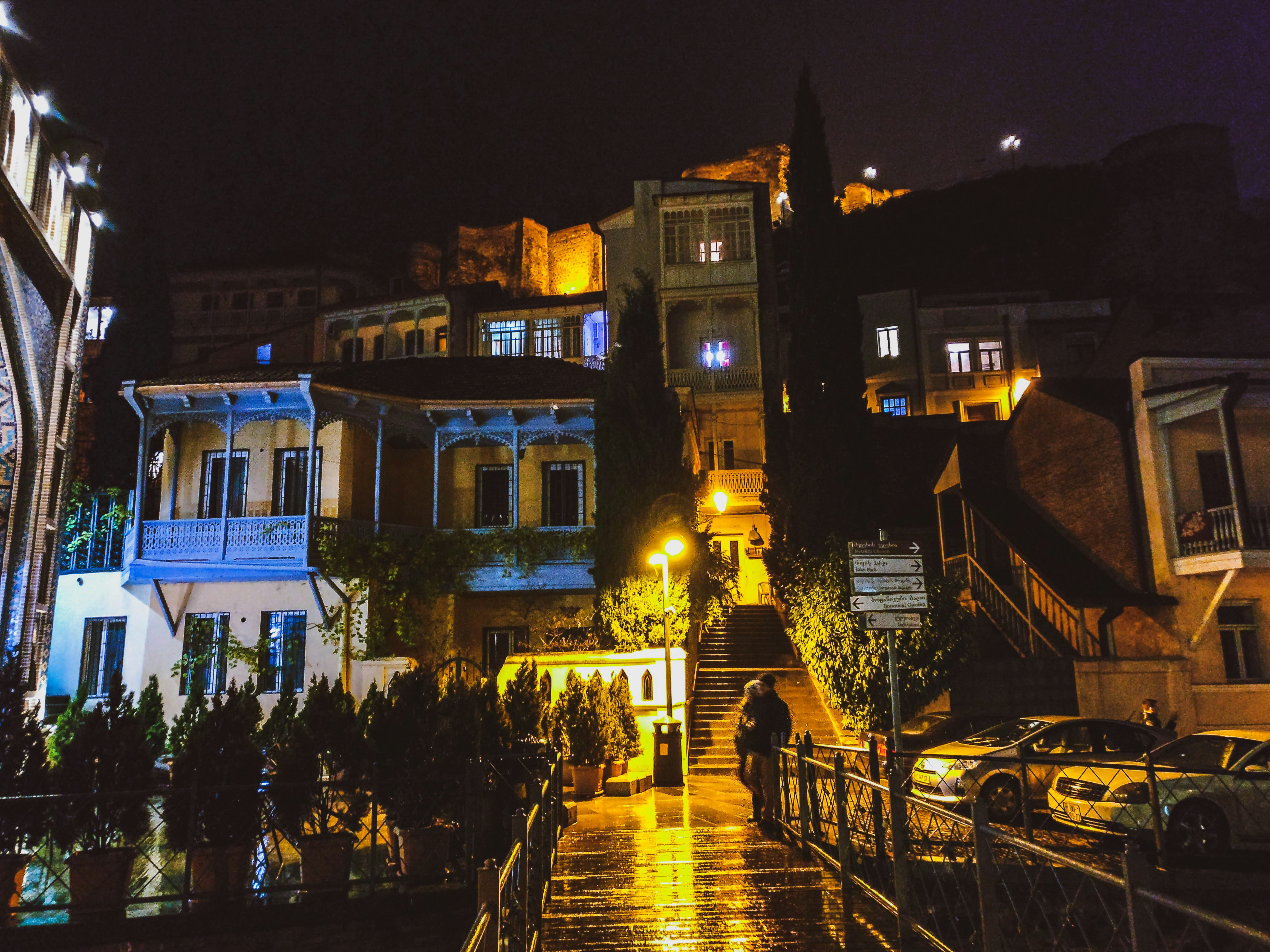 person standing beside railings near concrete lighted houses