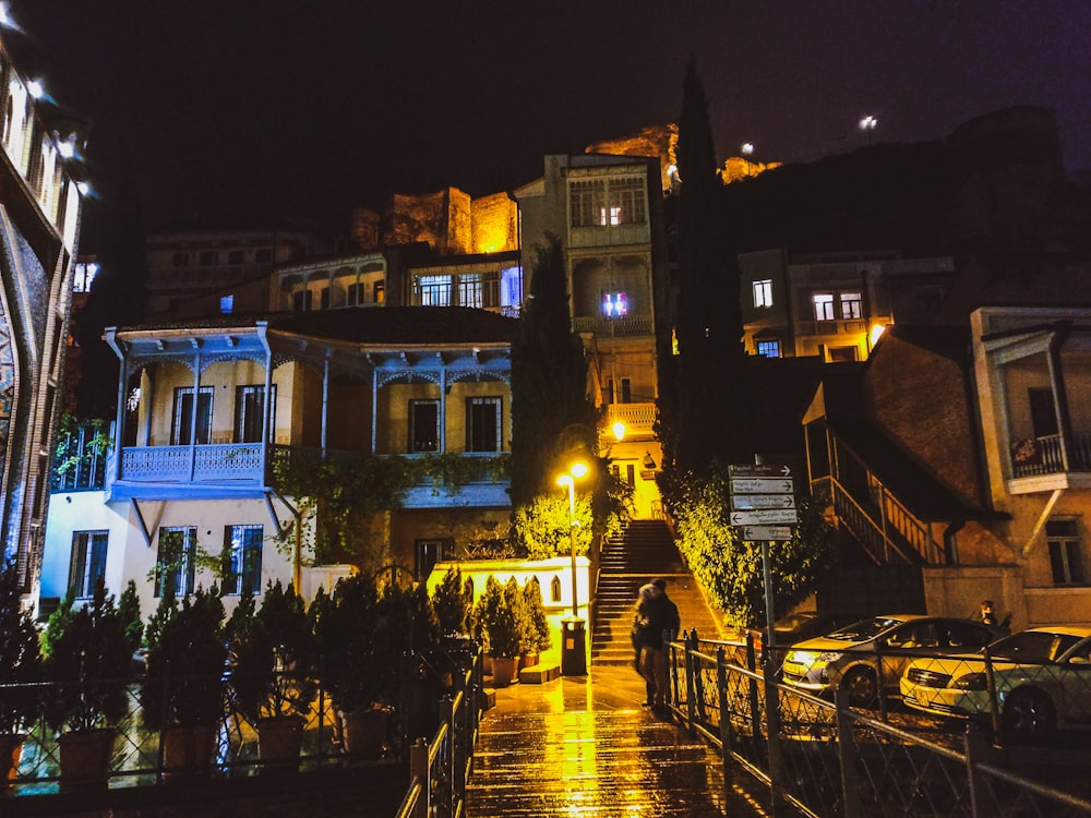 person standing beside railings near concrete lighted houses