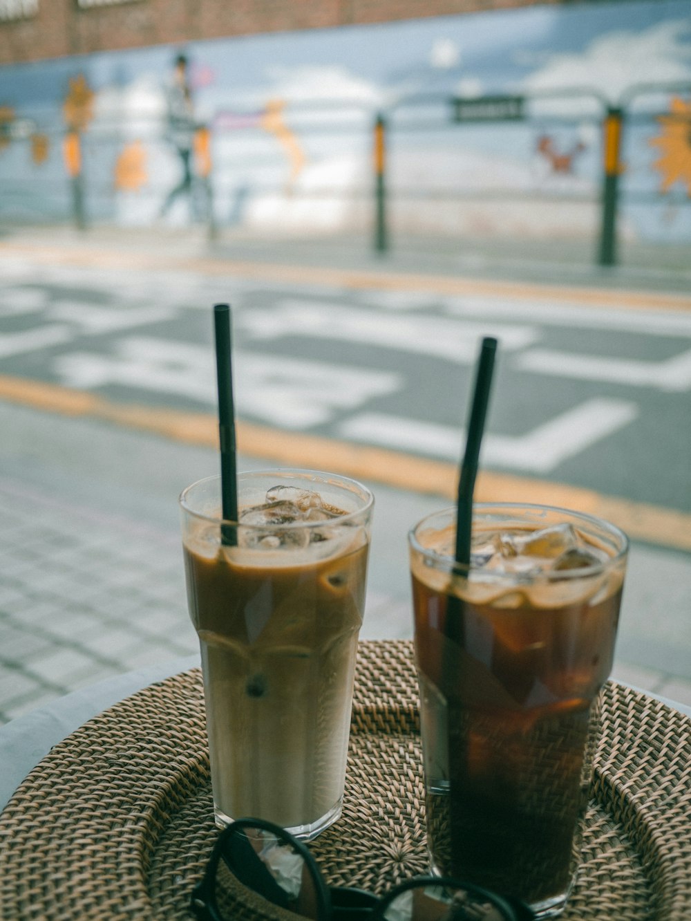 Two ice cold coffee drinks in drinking glasses near black framed