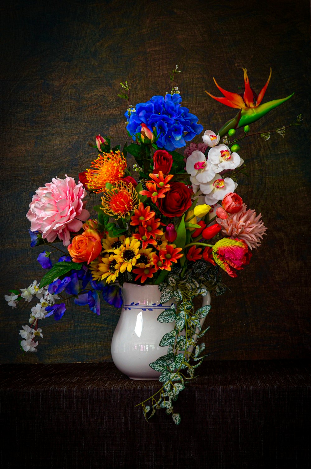 verschiedene Blumen in weißer Vase auf brauner Oberfläche