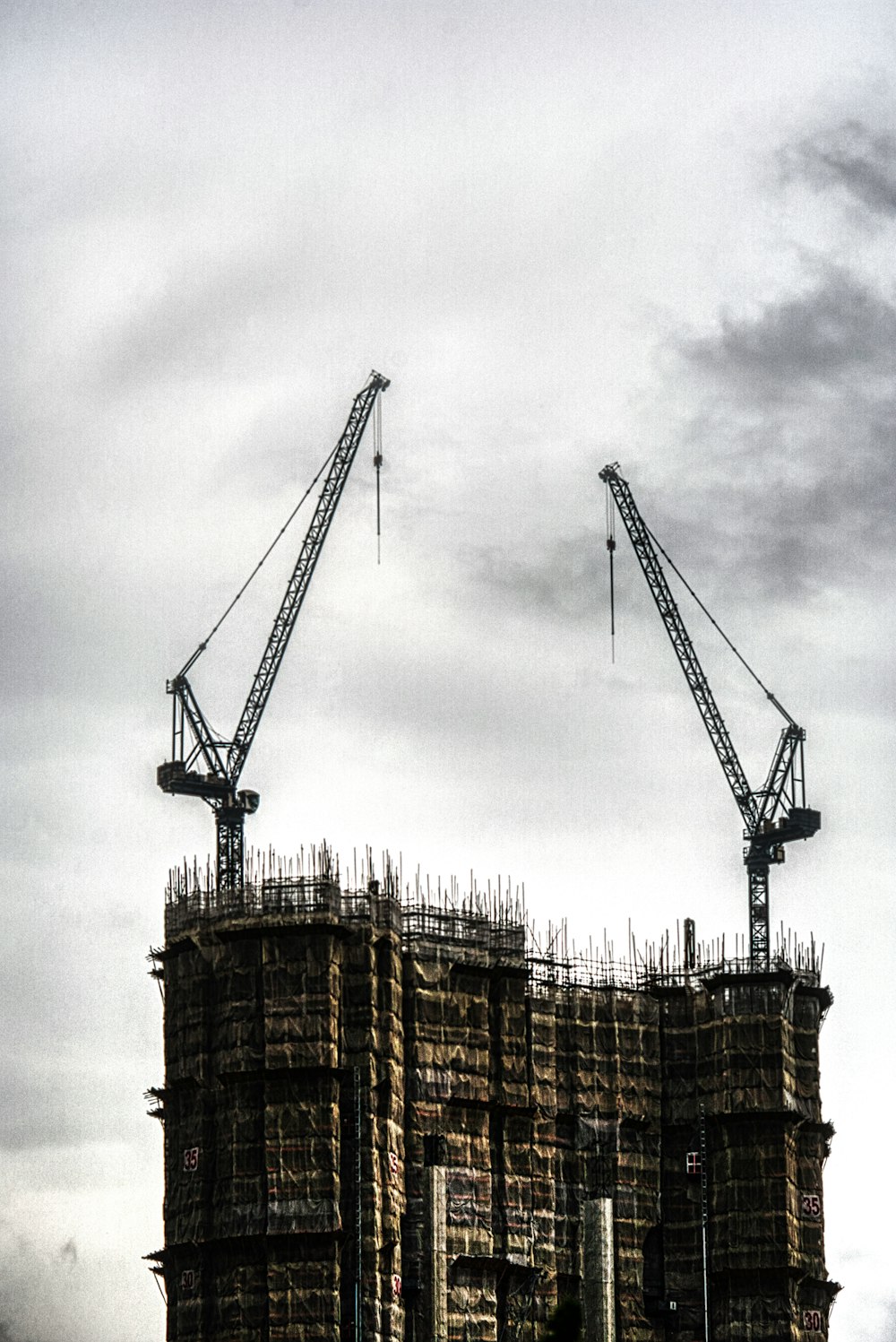 two cranes on top of unfinished building during day