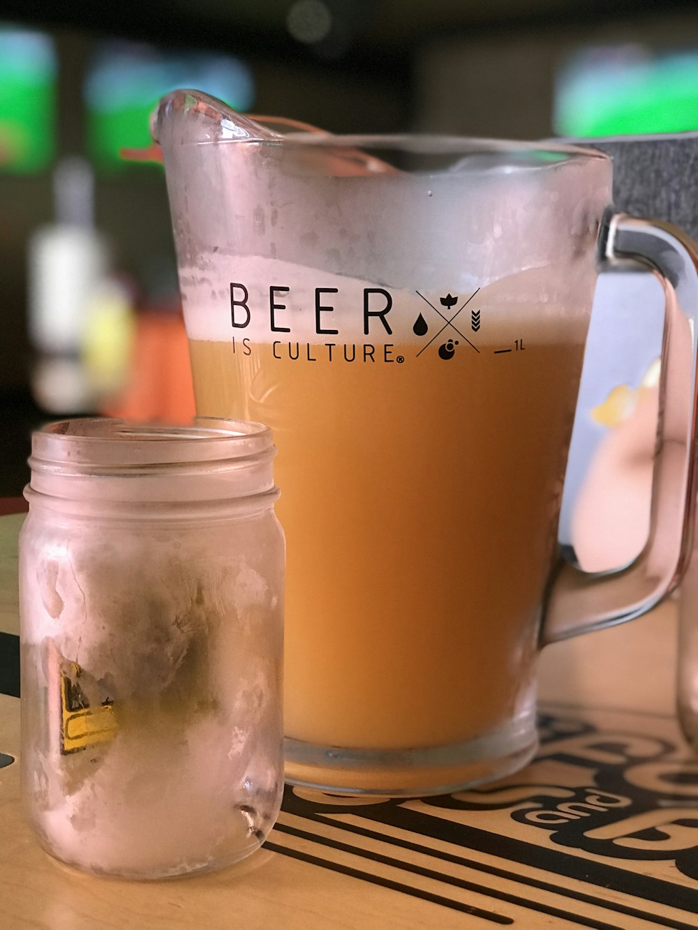 beverage filled pitcher beside empty jar