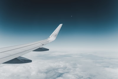 white airplane flying over the clouds aircraft teams background