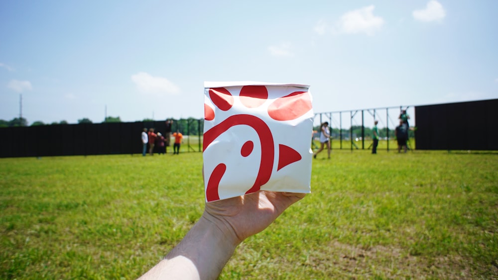 person holding white and red box