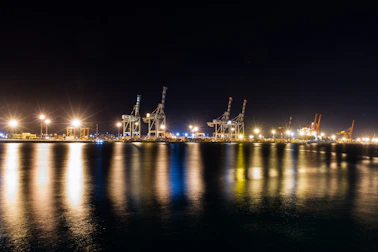 Nighttime view of a ship unloader illuminated by bright floodlights while unloading wheat.