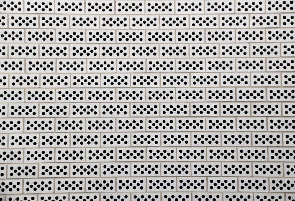 a white perfored wall with black dots on it