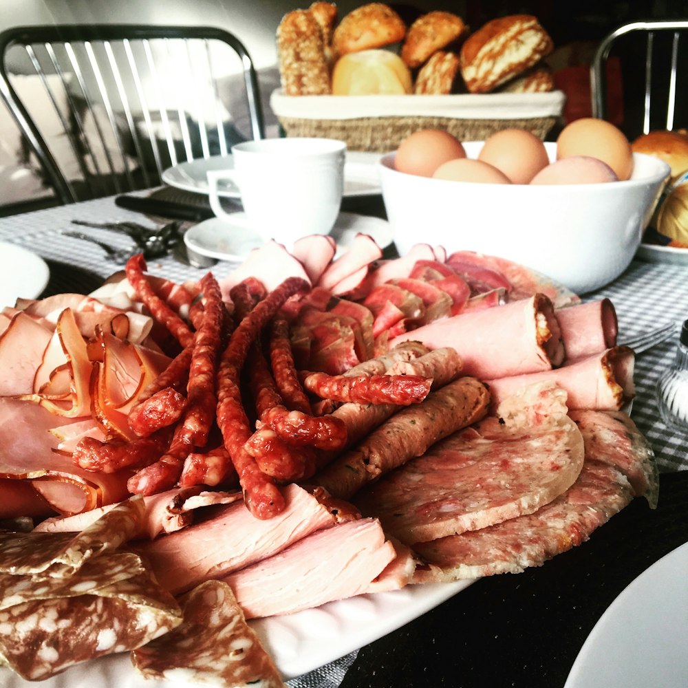 saucisses près du jambon tranché à côté des œufs de poule dans un bol sur la table