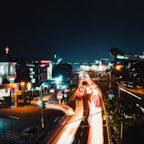 A wide-angle shot of a bustling city street at night, alive with colorful lights and movement.