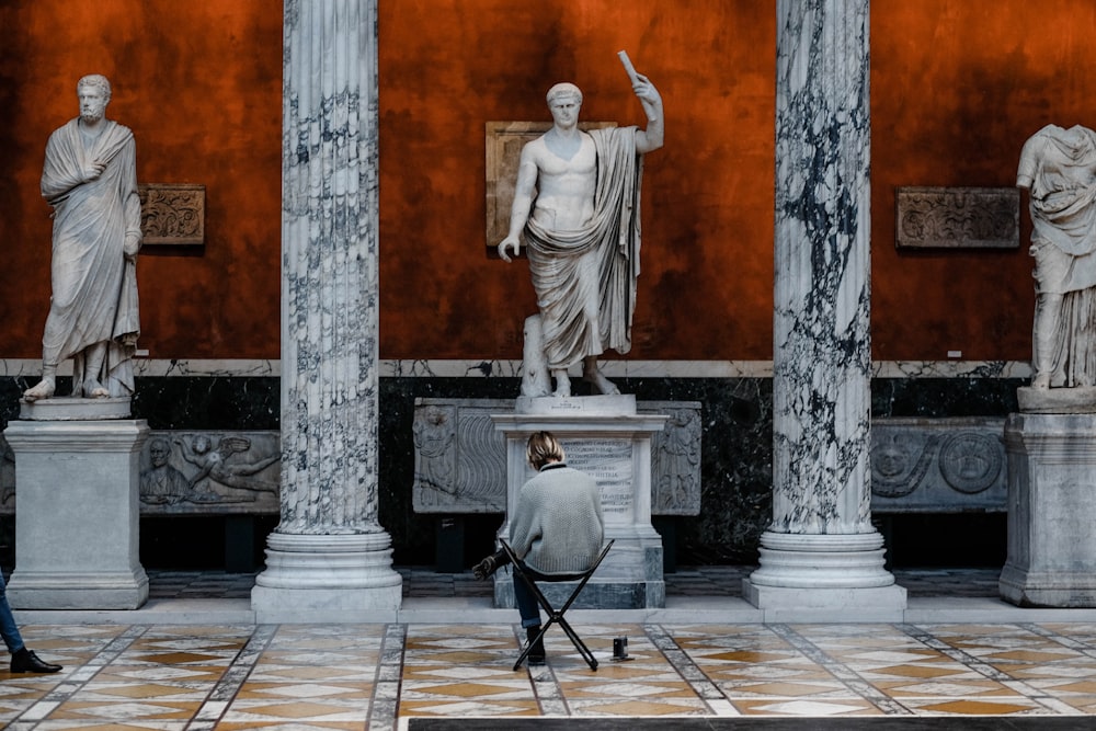 pessoa sentada na cadeira com pernas cruzadas perto da estátua de três homens