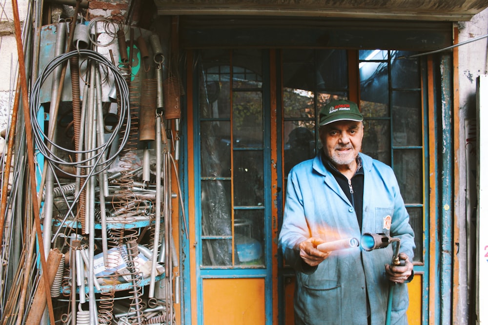 smiling man standing in front of closed door holding blow torch