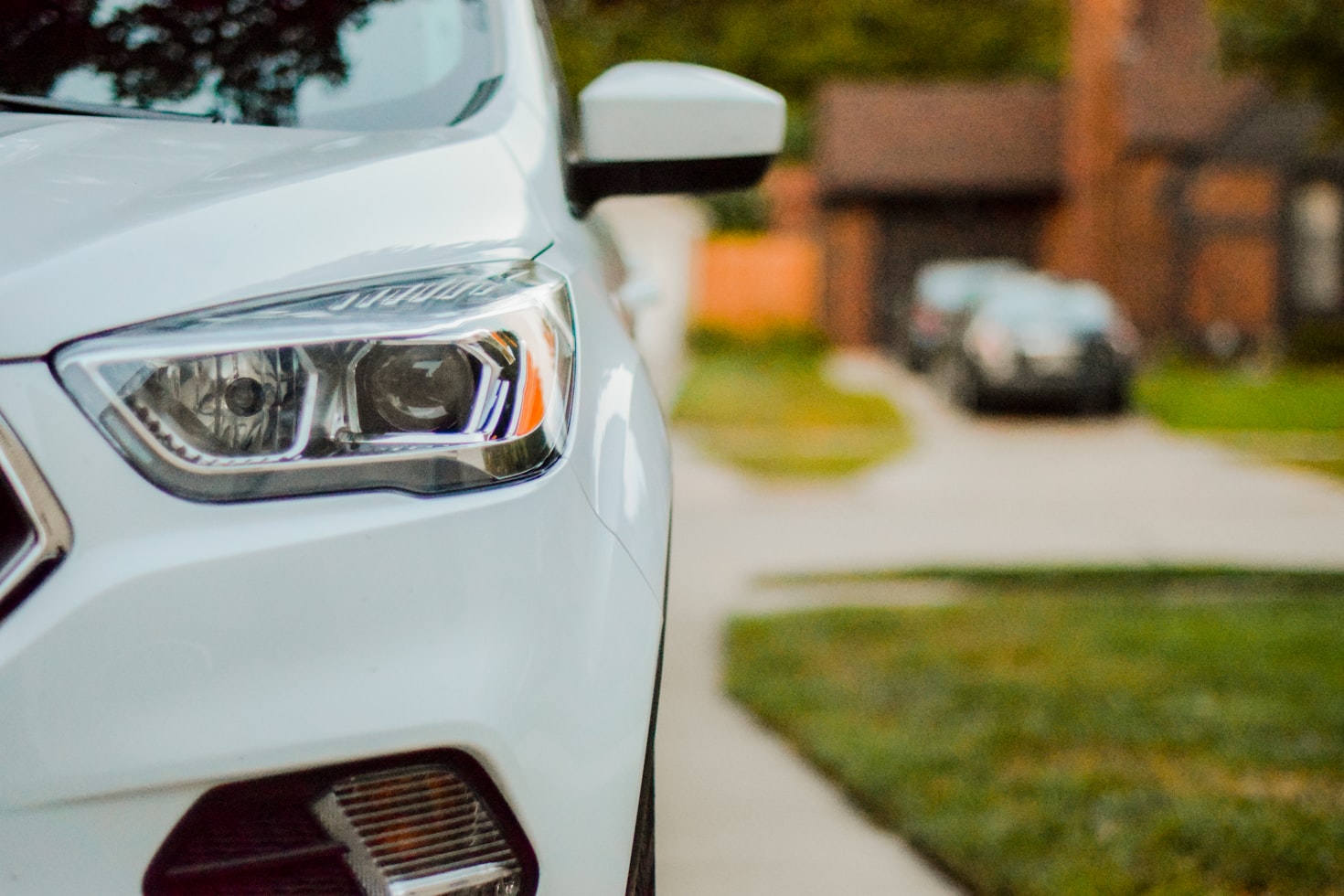 Drivers side headlight of a white car in a driveway