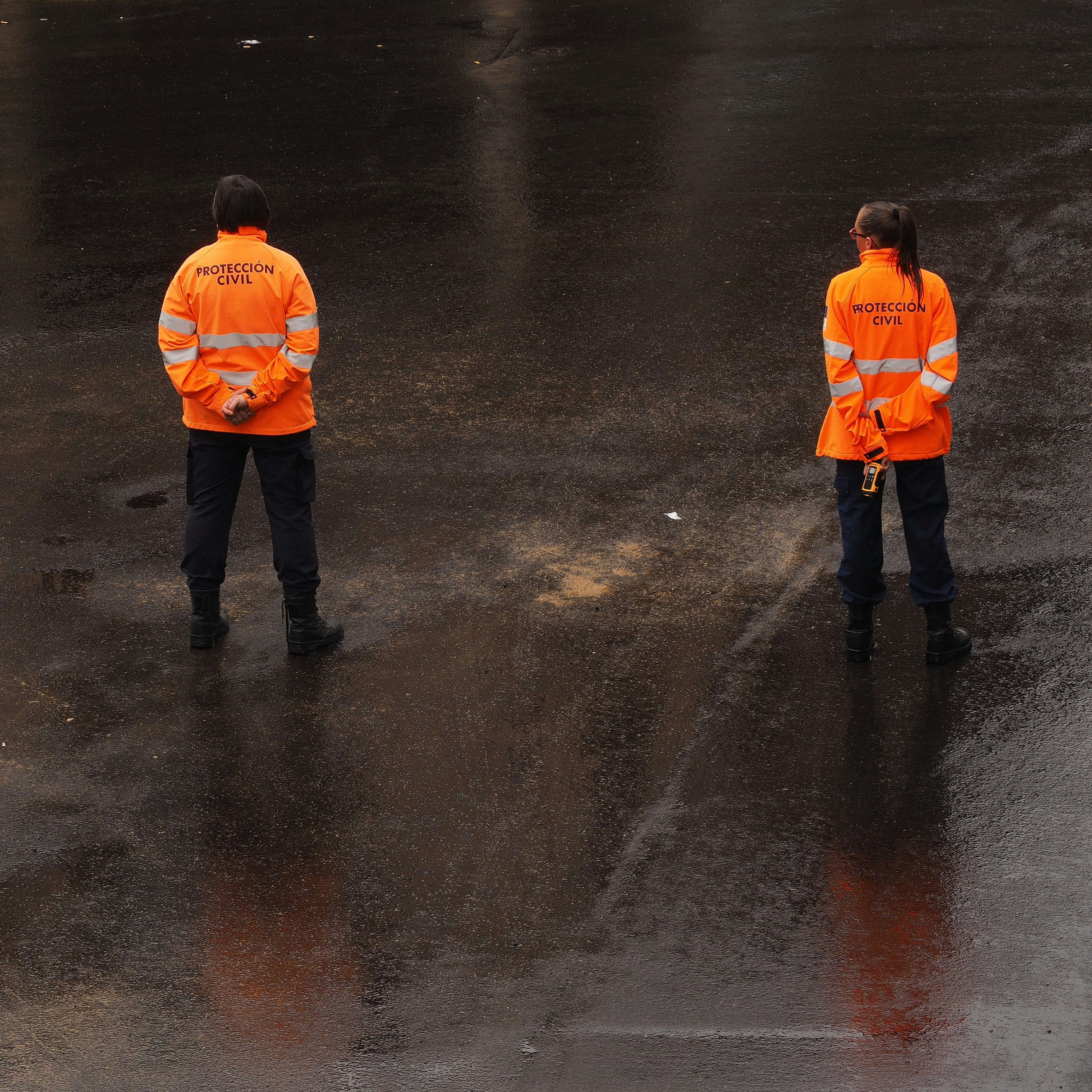 two woman wearing orange-and-gray jackets