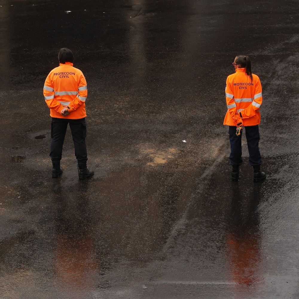 two woman wearing orange-and-gray jackets