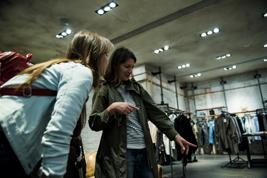 two women standing near hanging clothes